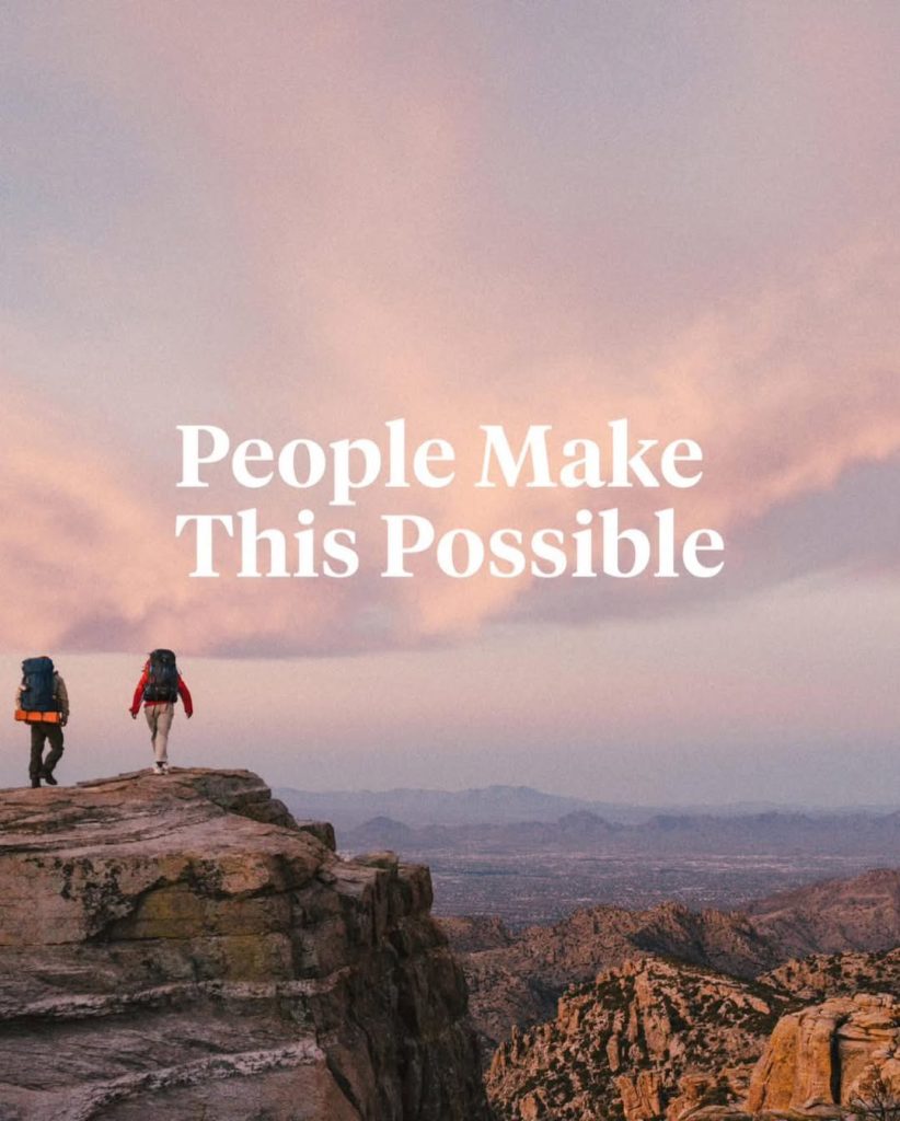 Two hikers on cliff edge with inspirational quote
