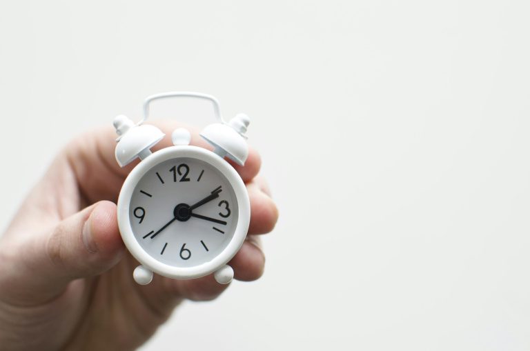 A golden sun setting behind a clock face, symbolizing the end of the biannual time change